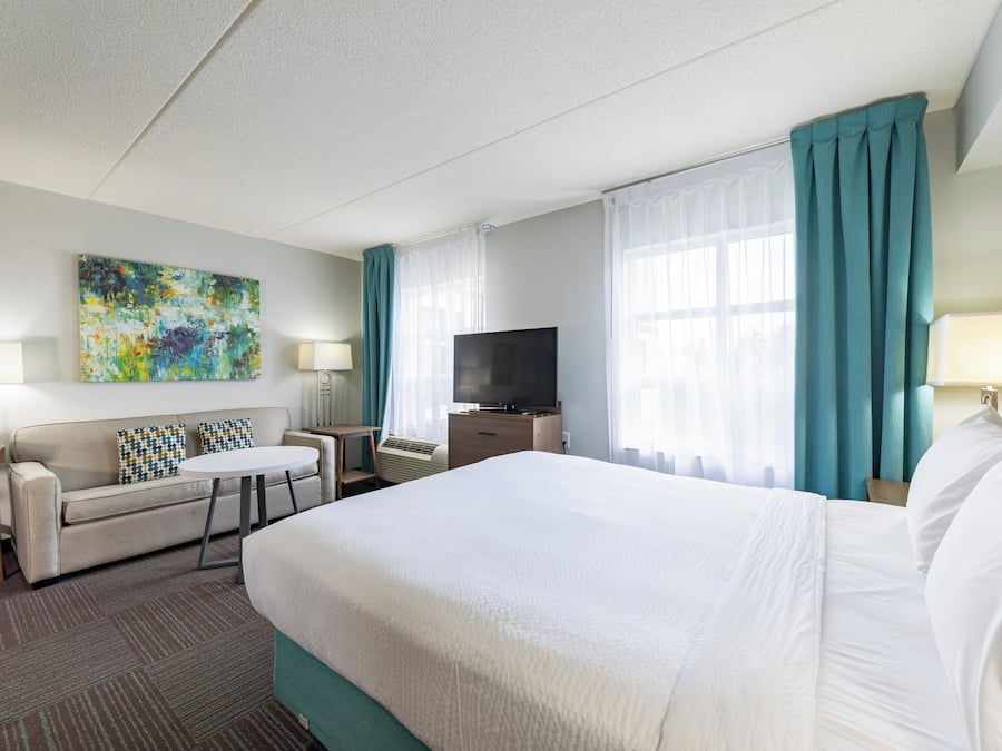 Een hotelkamer met een groot bed, een bank, een televisie en een schilderij aan de muur.