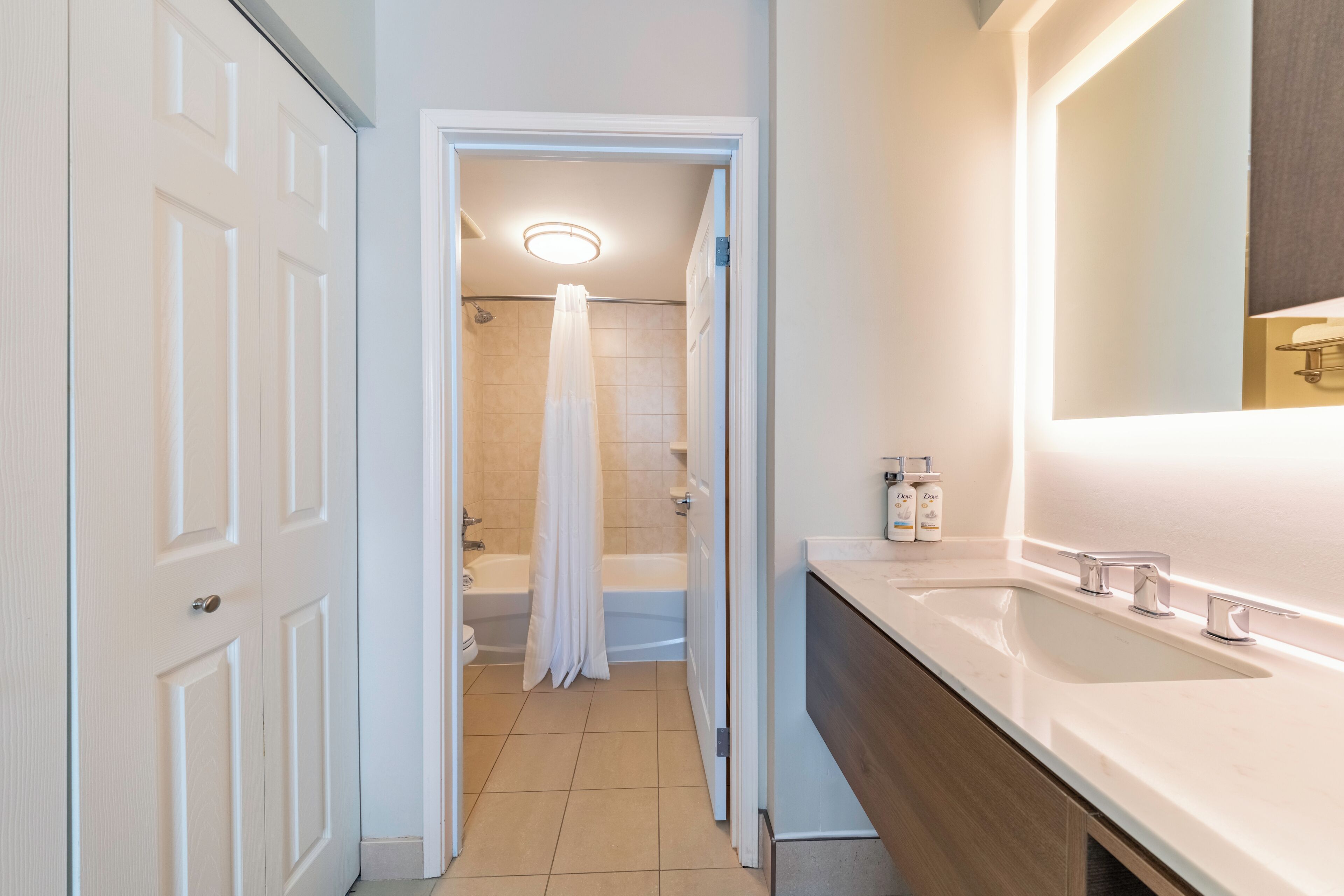 Un baño moderno con un lavamanos blanco, un espejo y una ducha con cortina.