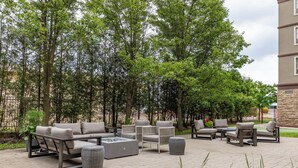 An outdoor patio area with a sofa set, chairs, and a fire pit. - Staybridge Suites Guelph by IHG (Guelph)