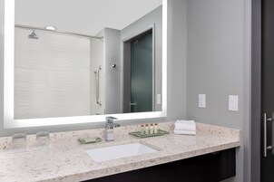 Un baño moderno con un espejo grande, un lavabo y una ducha.