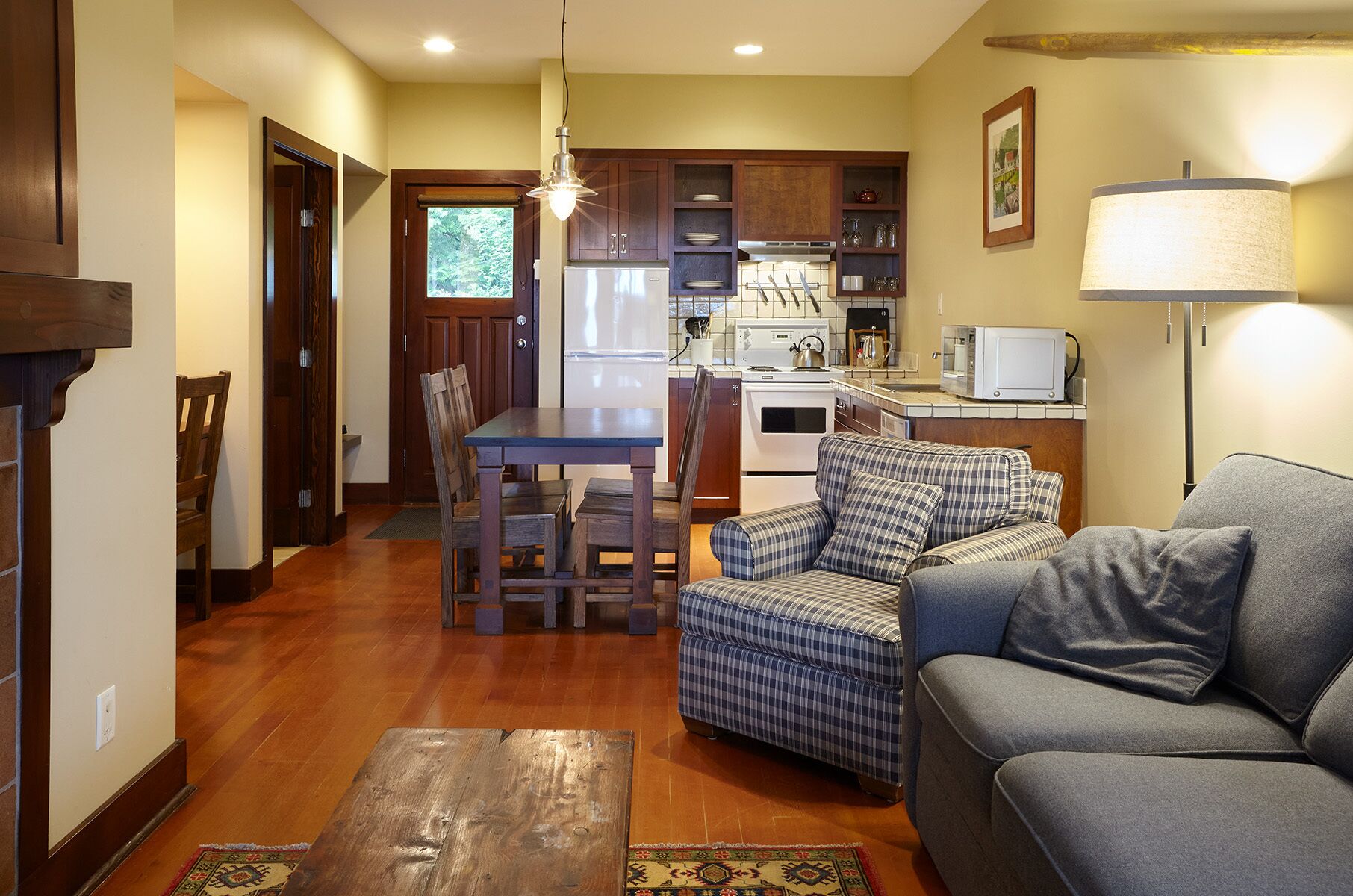 A cozy living room with a sofa, a plaid chair, and a wooden coffee table.