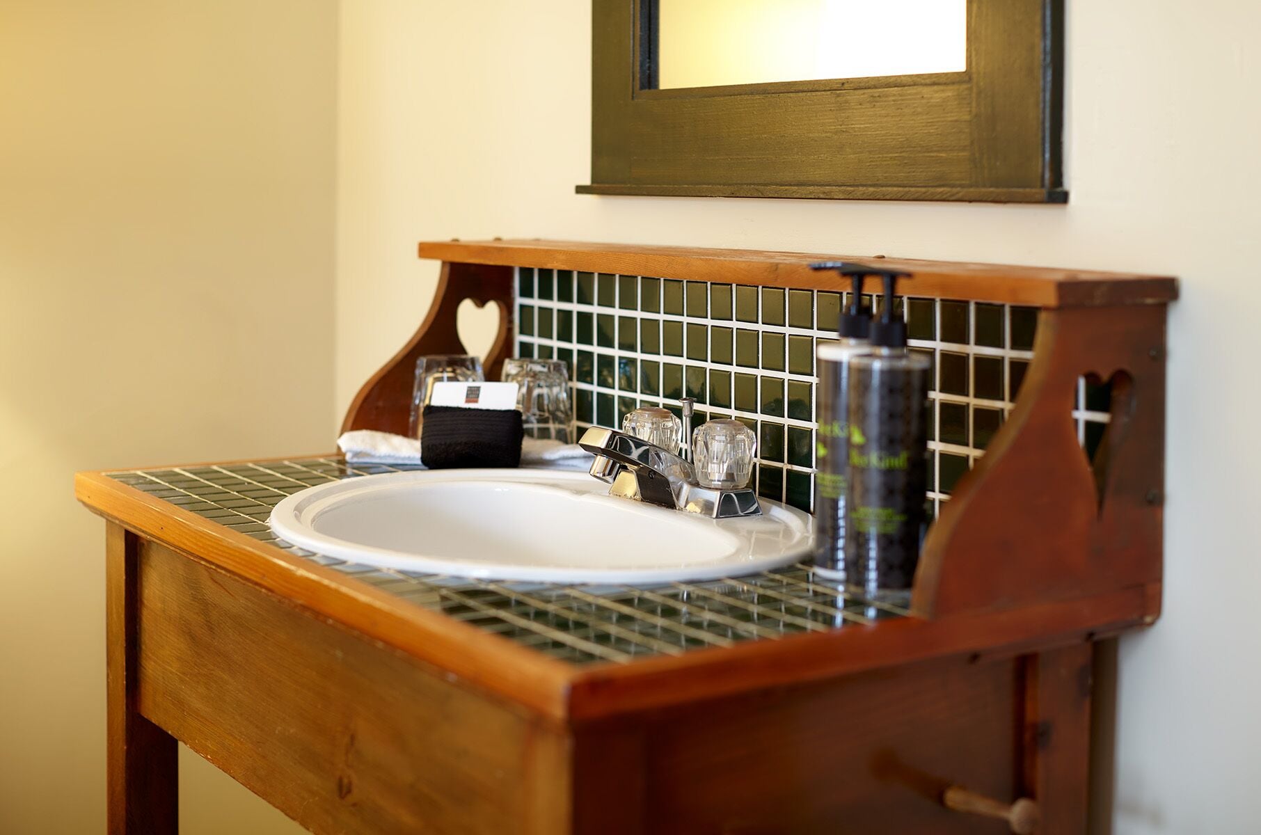 A bathroom with a wooden vanity, a white sink, and a mirror above it.