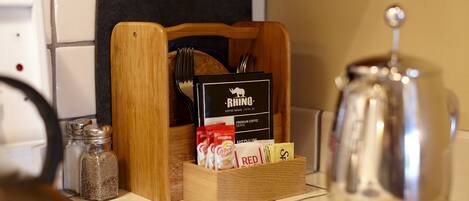 A kitchen counter with a coffee maker, a wooden box containing coffee beans and a coffee menu, and salt and pepper shakers.