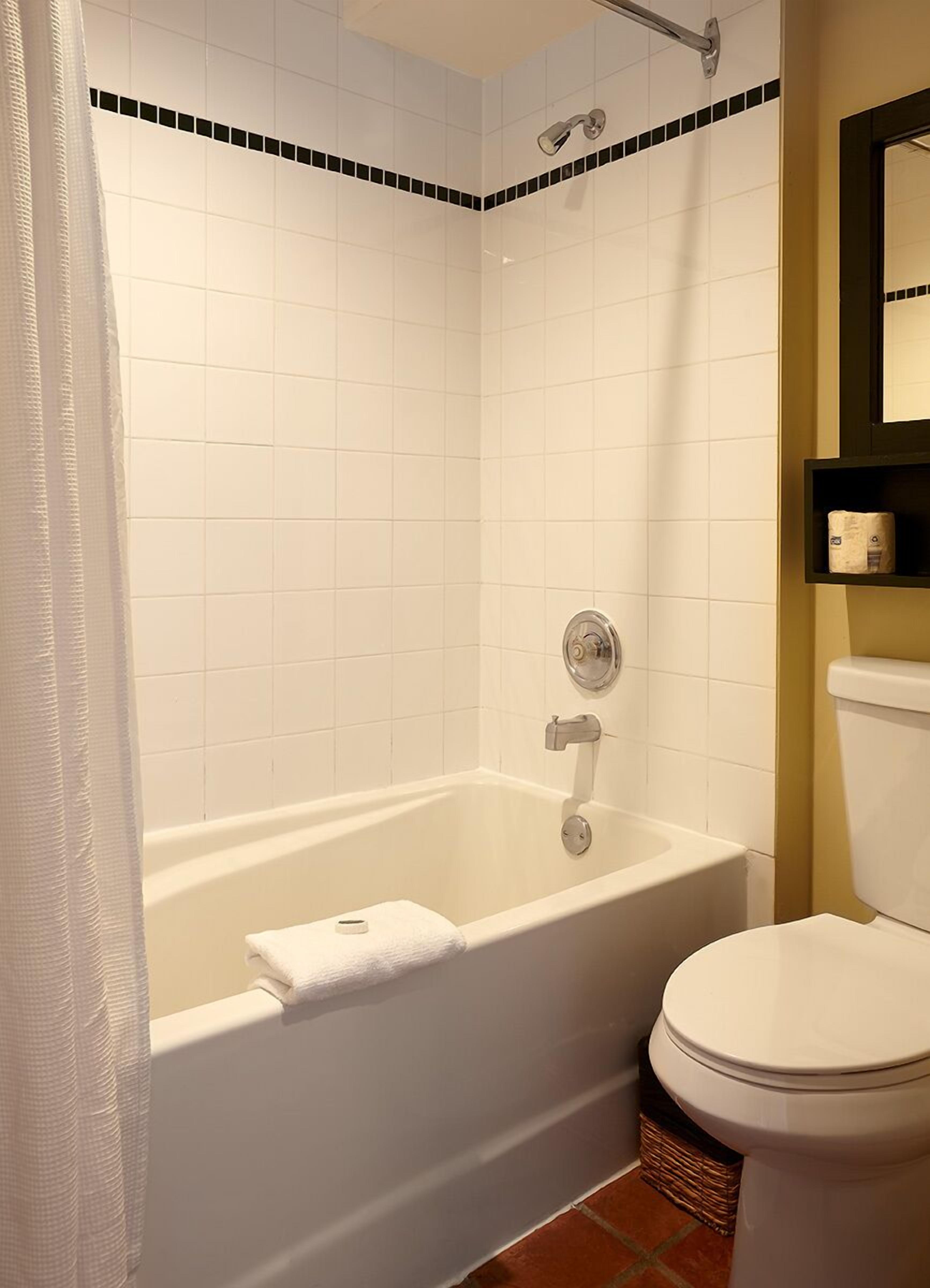 A bathroom with a bathtub, toilet, and a showerhead.
