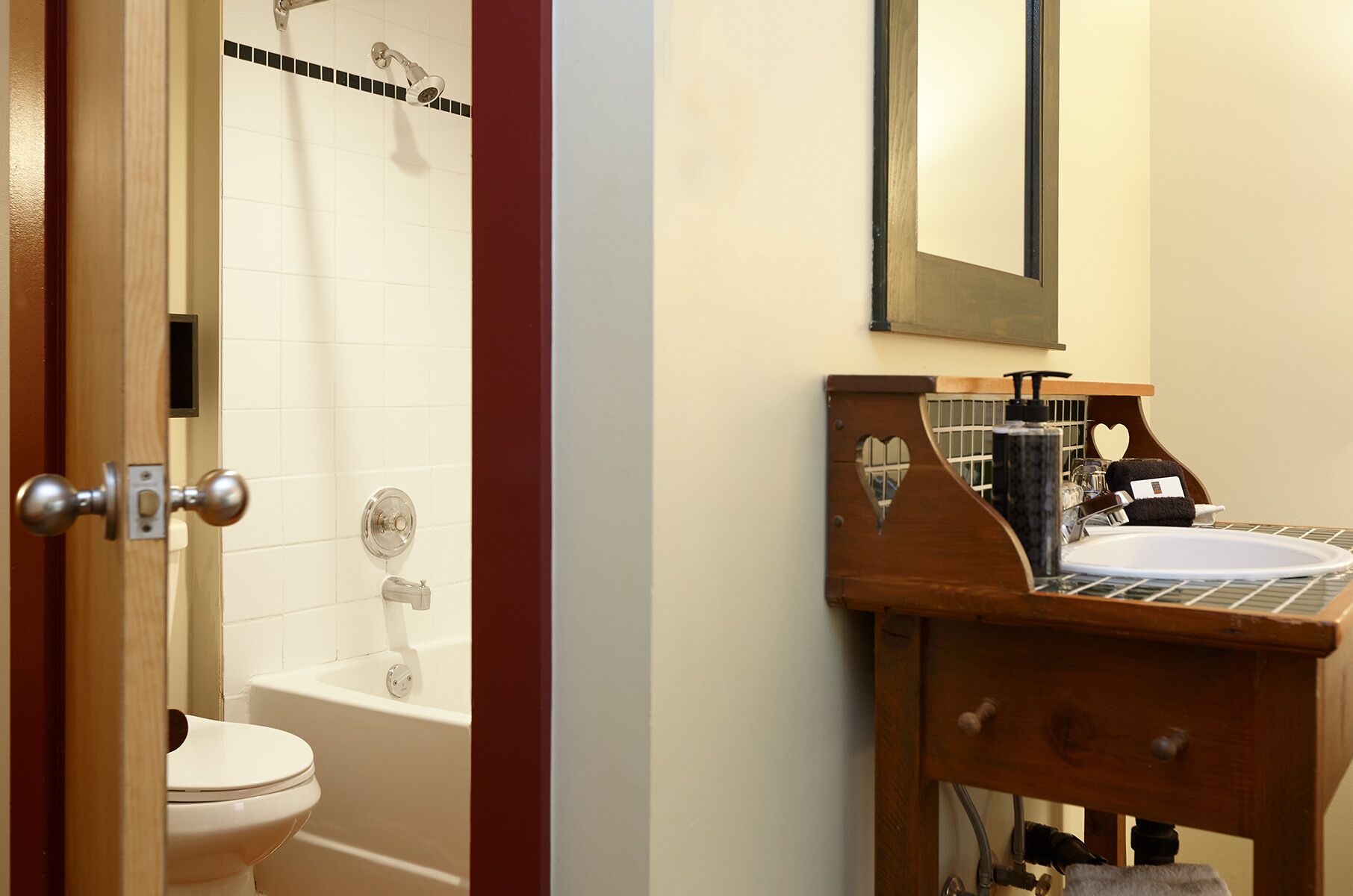 A bathroom with a white toilet, a bathtub, and a wooden vanity with a sink.