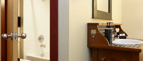 A bathroom with a white toilet, a bathtub, and a wooden vanity with a sink.