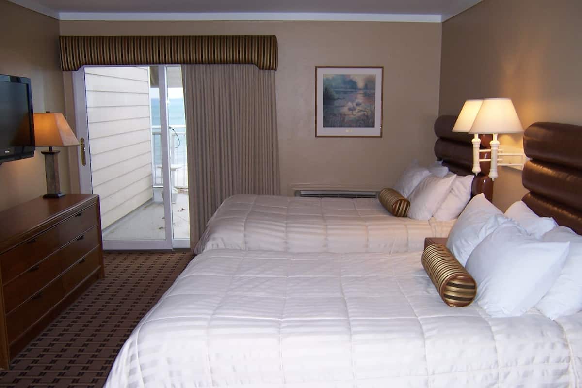 A hotel room with a large bed, two bedside lamps, a dresser, and a painting on the wall.