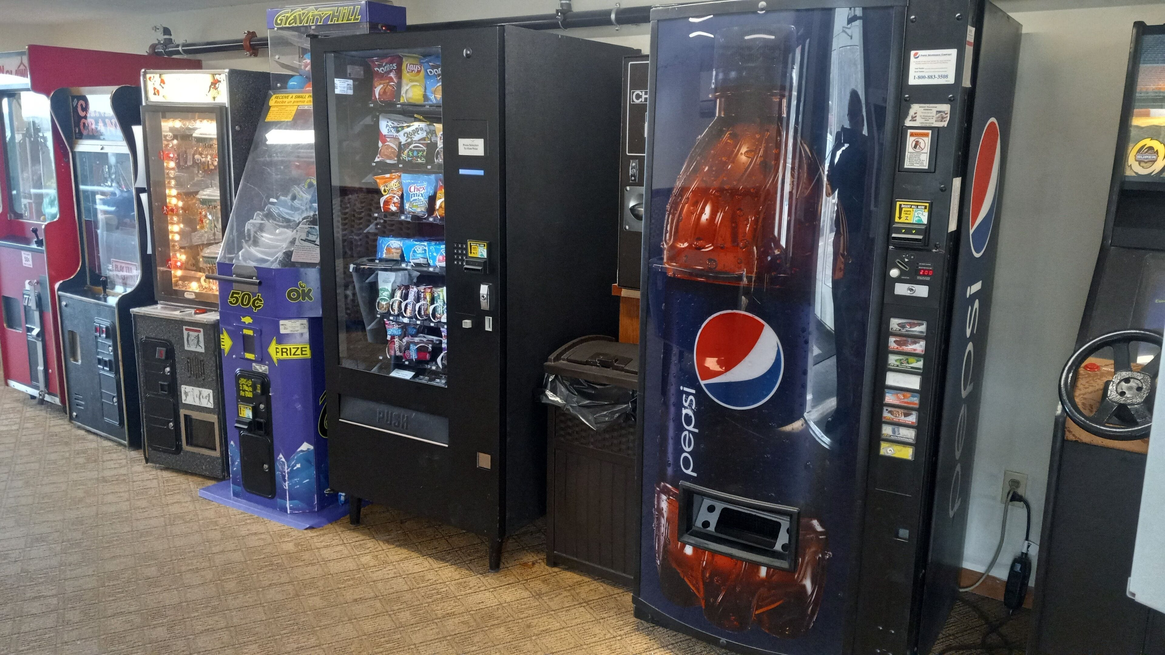Een rij automaten met verschillende snacks en drankjes, waaronder een Pepsi automaat.