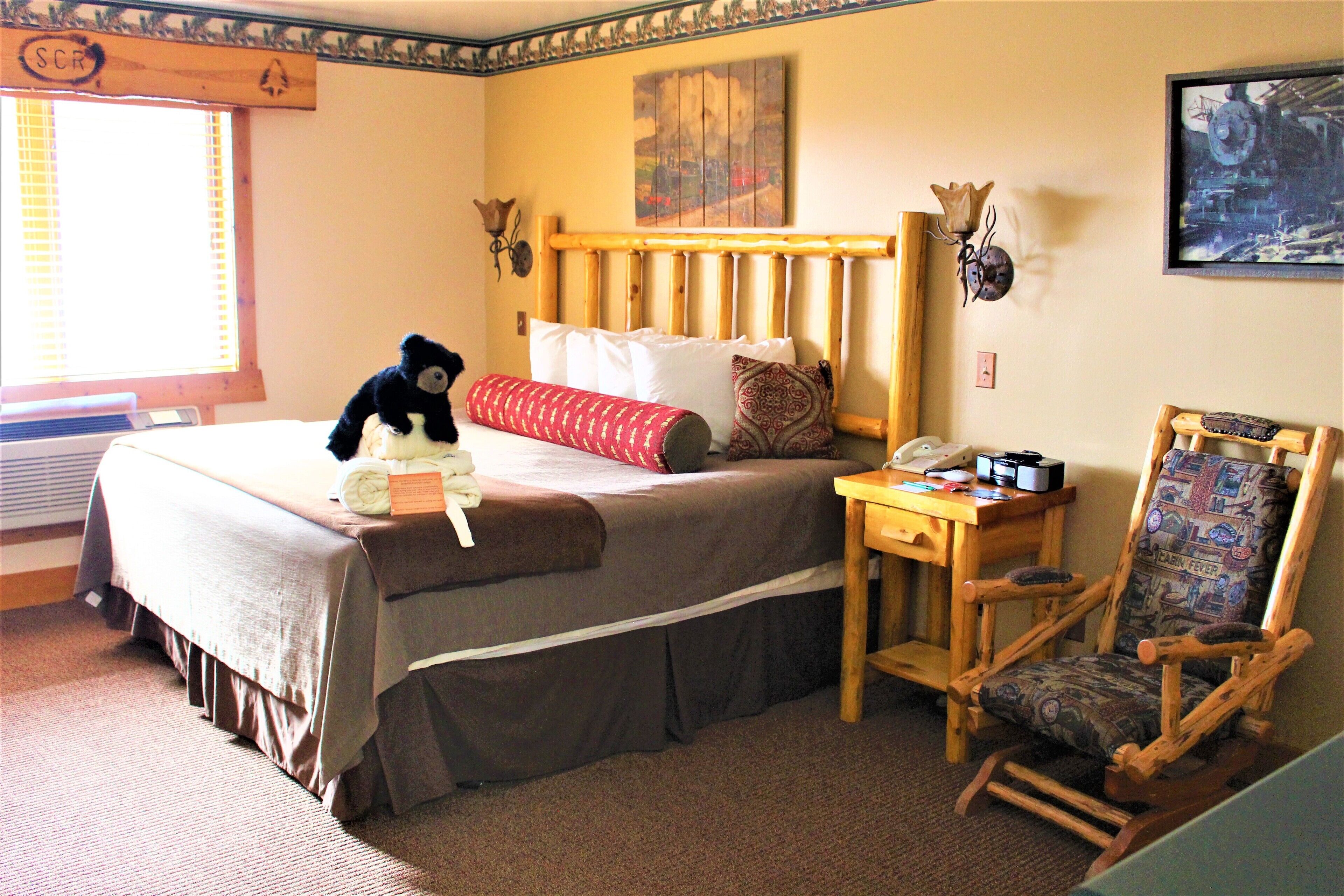 A bedroom with a bed, a wooden chair, a nightstand, and a window with blinds.