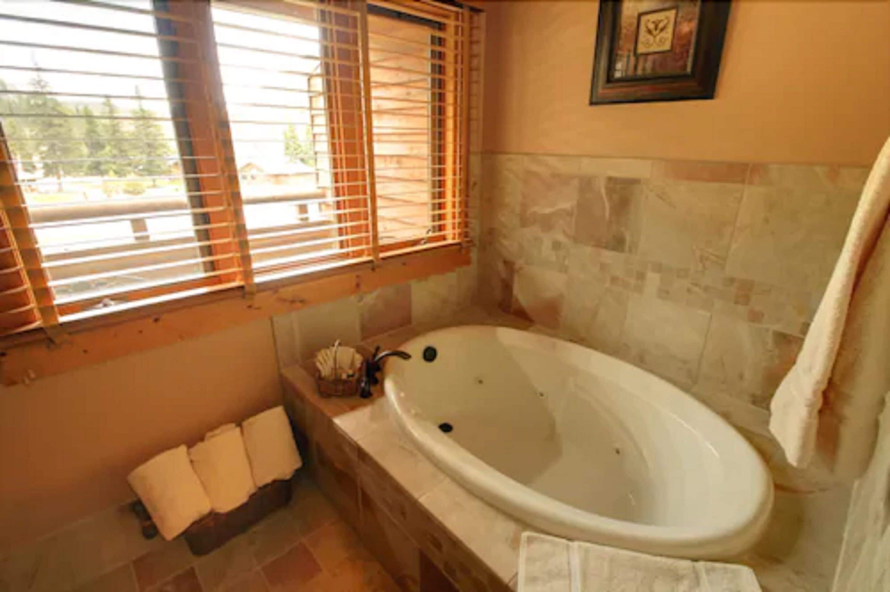 A bathroom with a freestanding bathtub, a window with blinds, and a towel rack.