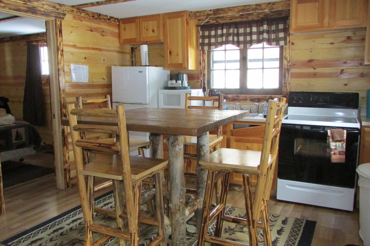 Una cocina de estilo rústico tipo cabaña con armarios de madera, una isla central y una estufa.