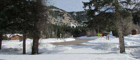 Schneebedeckte Landschaft mit einer Holzhütte, einer Straße und einem Stoppschild.