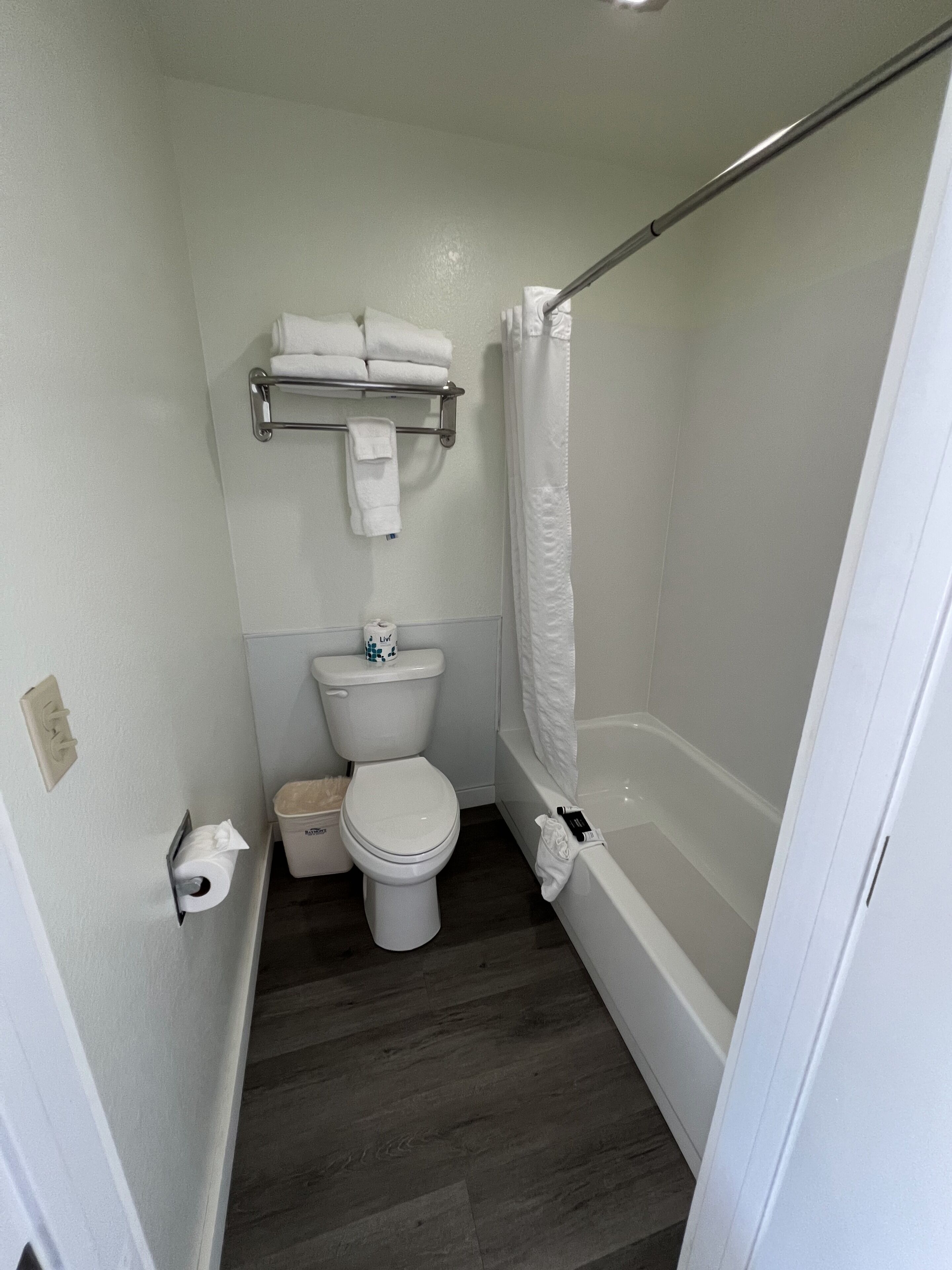 Een kleine, schone badkamer met toilet, douche en een handdoekhouder.