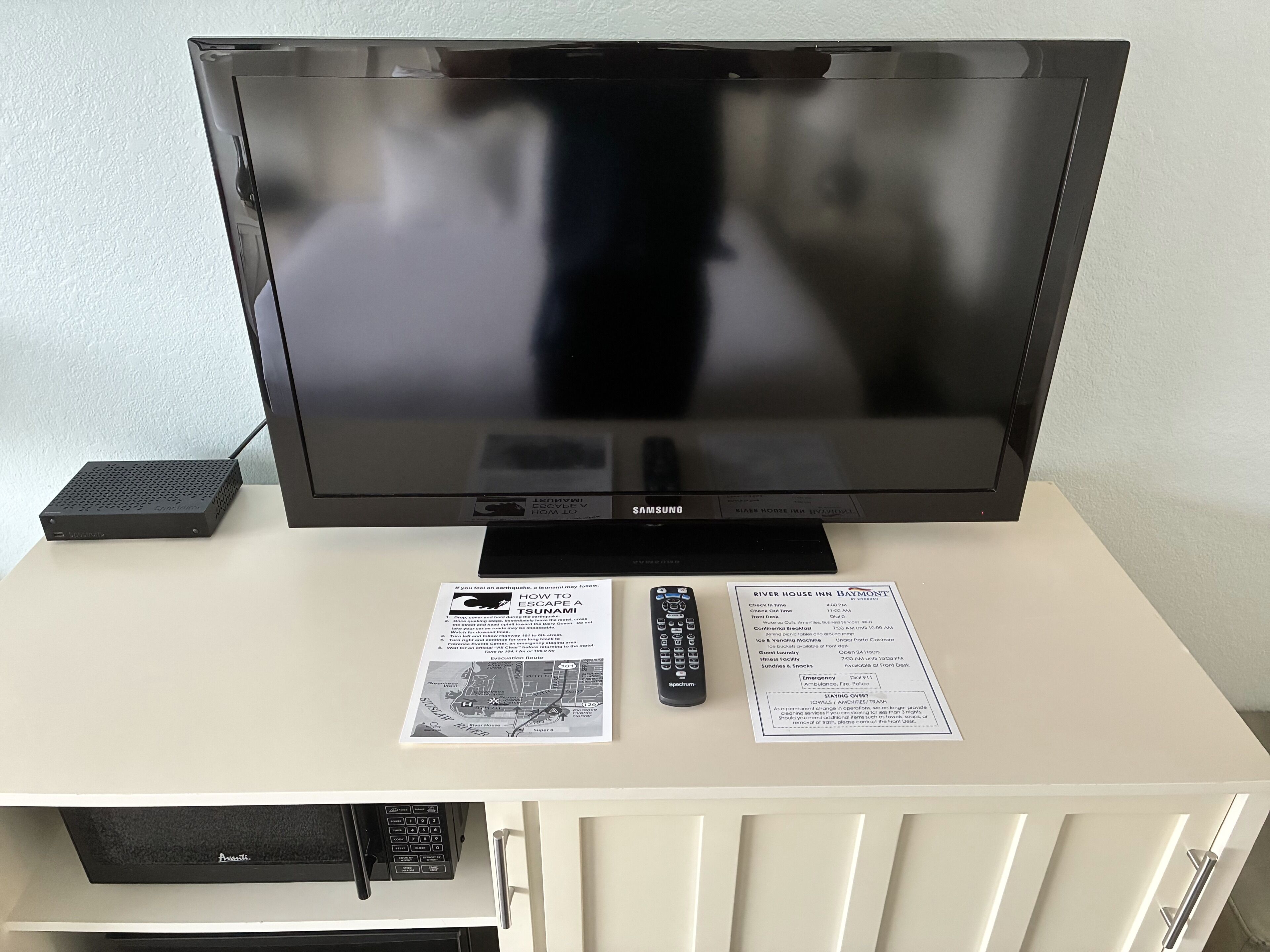 En tv, en fjärrkontroll och två informationskort placerade på ett vitt skåp.