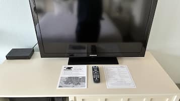 Televisor, comandament a distància i dues targetes informatives sobre un moble blanc.