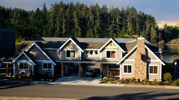 A two-story house with a stone chimney, a garage, and a driveway.