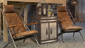 A vintage-style wooden cabinet with metal accents and two leather chairs with wooden armrests.