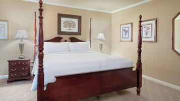 A four-poster bed with a wooden frame, a headboard, and a white bedspread. There are two bedside tables with lamps and a dresser with drawers.