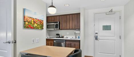 Una cocina moderna con armarios de madera, un microondas de acero inoxidable y una mesa de comedor de madera con sillas negras.