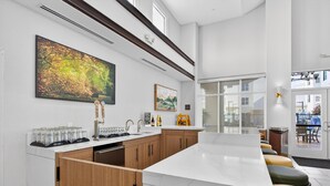 A modern kitchen with a marble countertop, wooden cabinets, and a large painting on the wall.