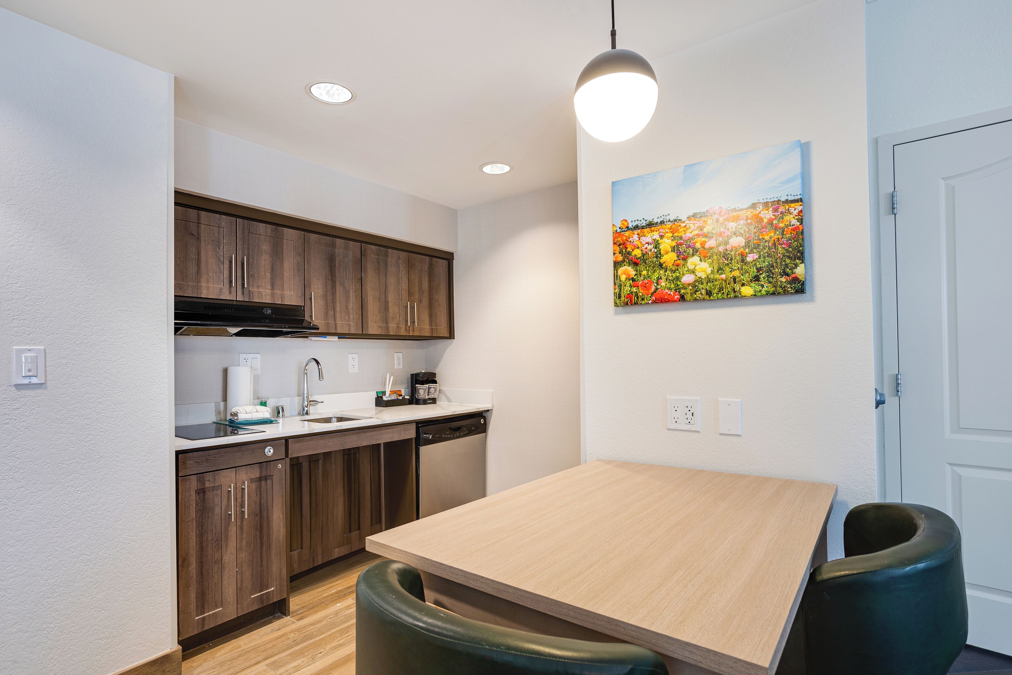A modern kitchen with wooden cabinets, a stainless steel range hood, and a light wooden dining table.