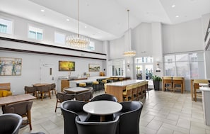 A spacious dining area with high ceilings, pendant lighting, and a central island with bar stools. - Homewood Suites by Hilton Carlsbad-North San Diego County (Carlsbad)