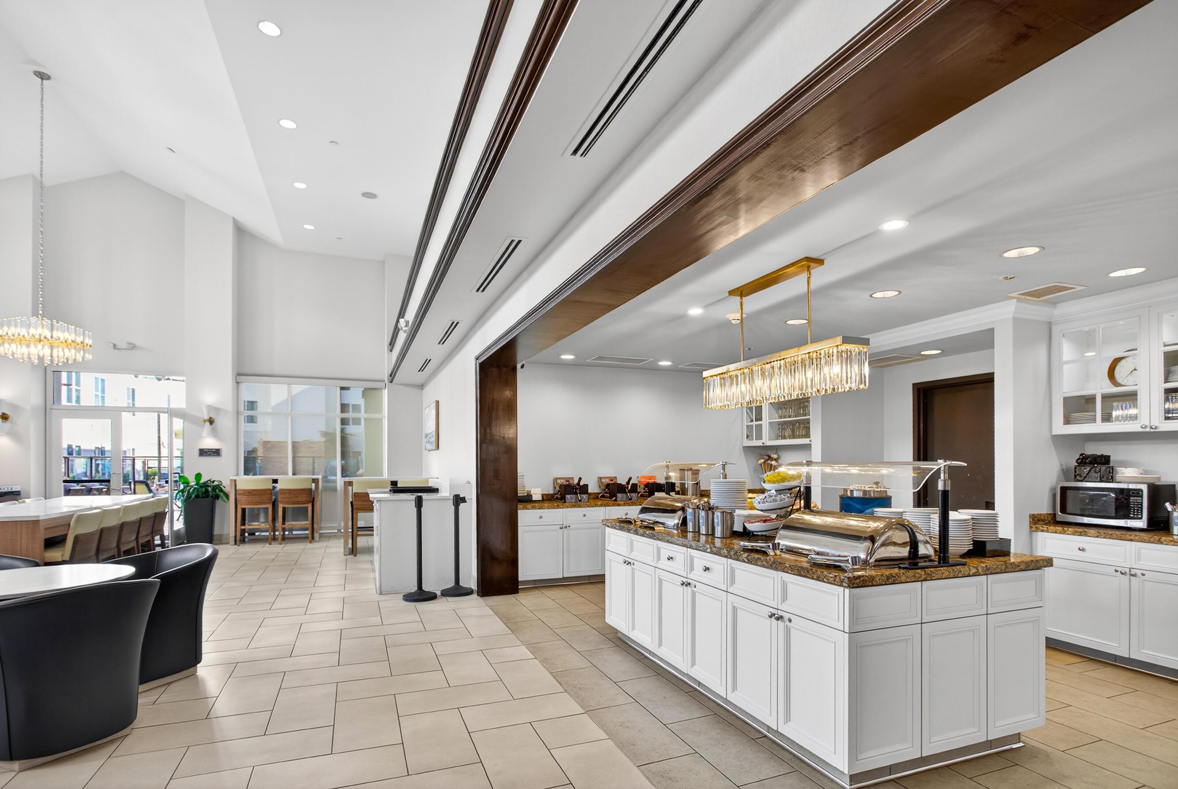 A modern kitchen with white cabinetry, granite countertops, and a breakfast bar.