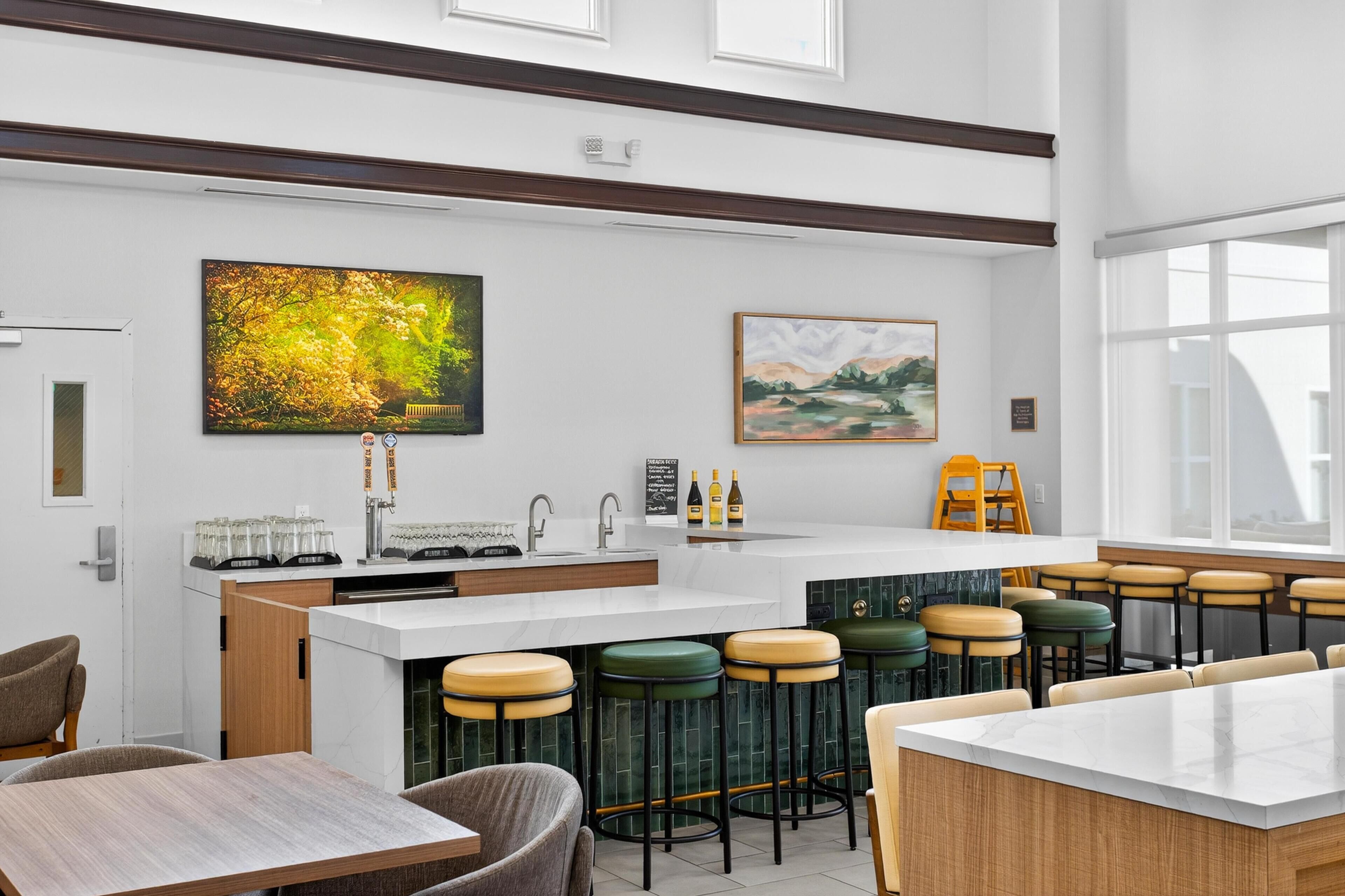A modern kitchen with a bar area, bar stools, and artwork on the walls.