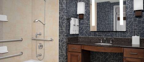 A modern bathroom with a bathtub, shower, vanity with a sink, and a large mirror.