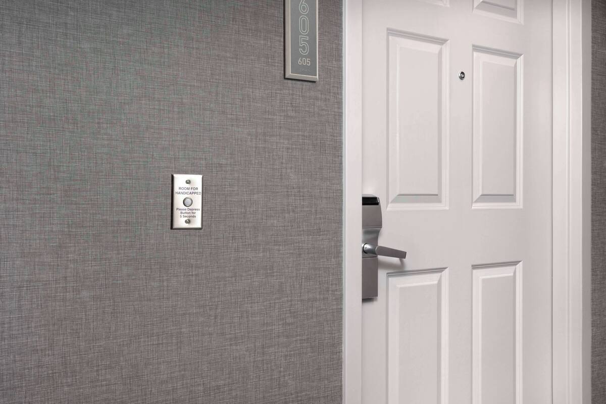A door with a sign indicating a room for handicapped individuals and a request to depress the door for 5 seconds.