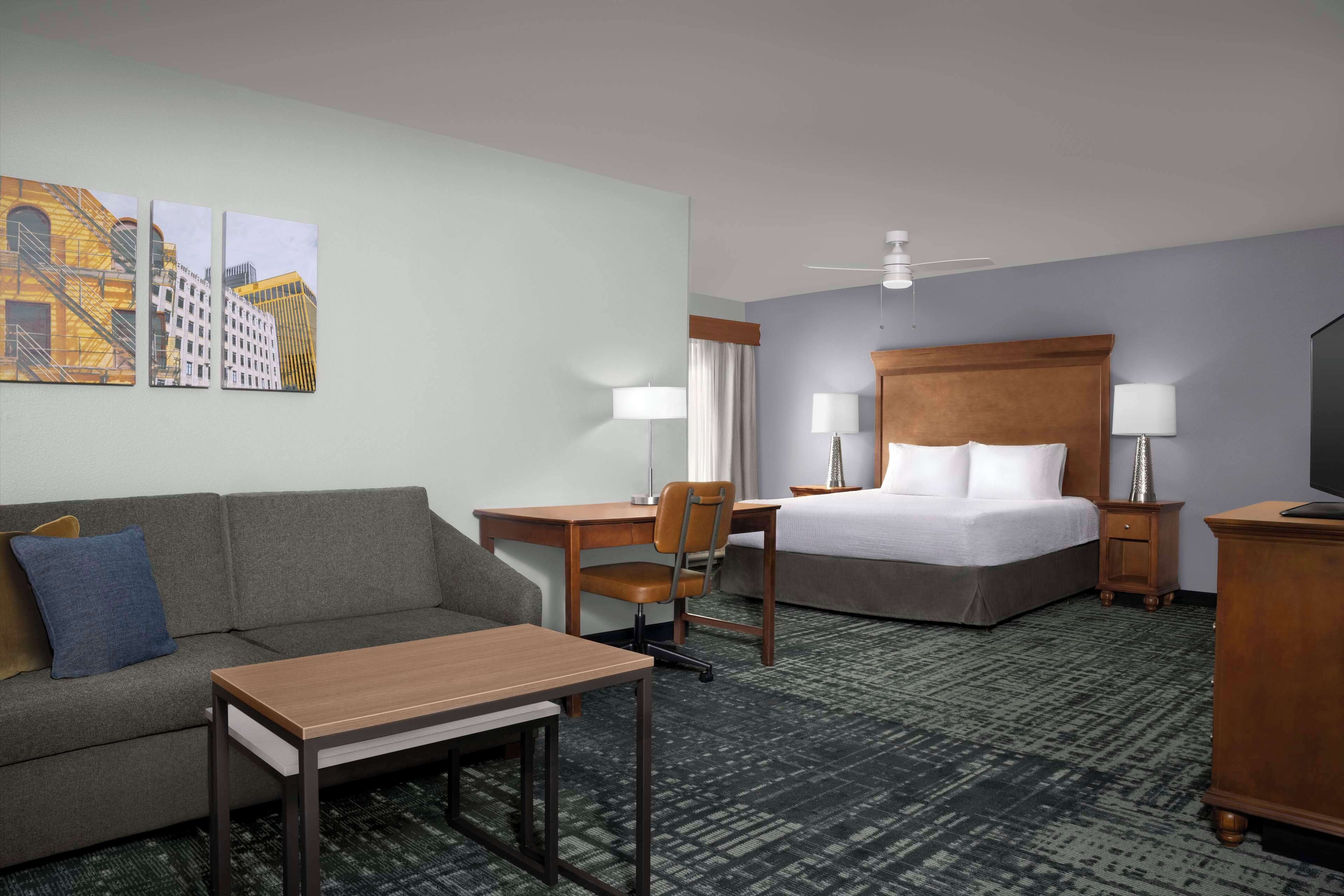 Ein Hotelzimmer mit Bett, Schreibtisch, Sessel, Sofa und einem kleinen Tisch.