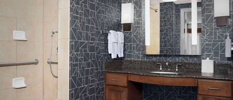 A modern bathroom with a shower, vanity, and a large mirror.
