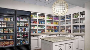 Une cuisine dotée d’un îlot central, de deux réfrigérateurs étiquetés « PLUS FROID » et « FROID », et d’étagères remplies de divers produits alimentaires et boissons.