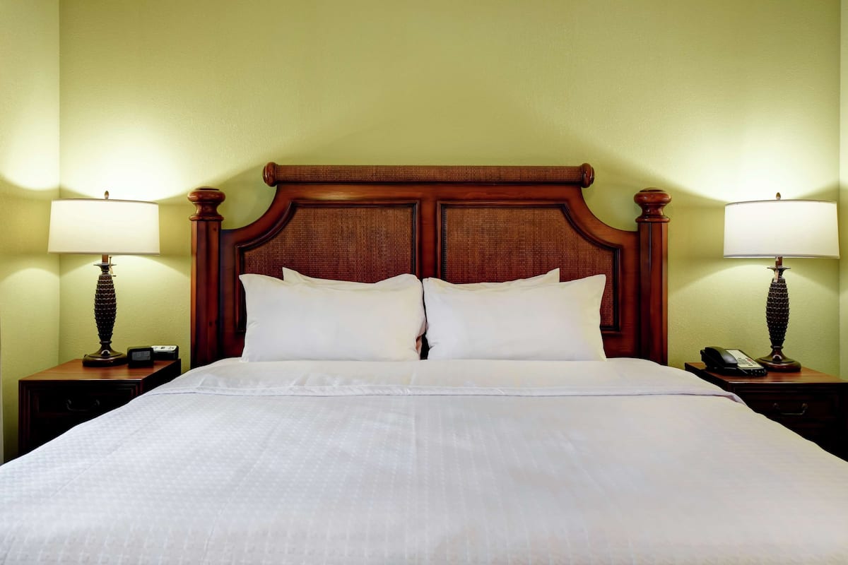 A neatly made bed with a wooden headboard, two bedside tables with lamps, and a telephone on one of the tables.