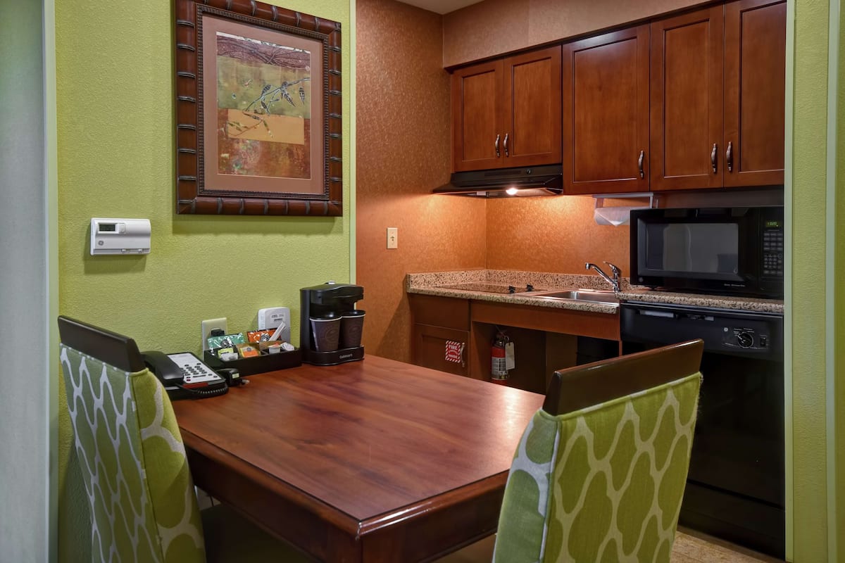 A compact kitchen with wooden cabinets, a microwave, and a coffee maker on the counter.