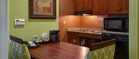 A compact kitchen with wooden cabinets, a microwave, and a coffee maker on the counter.