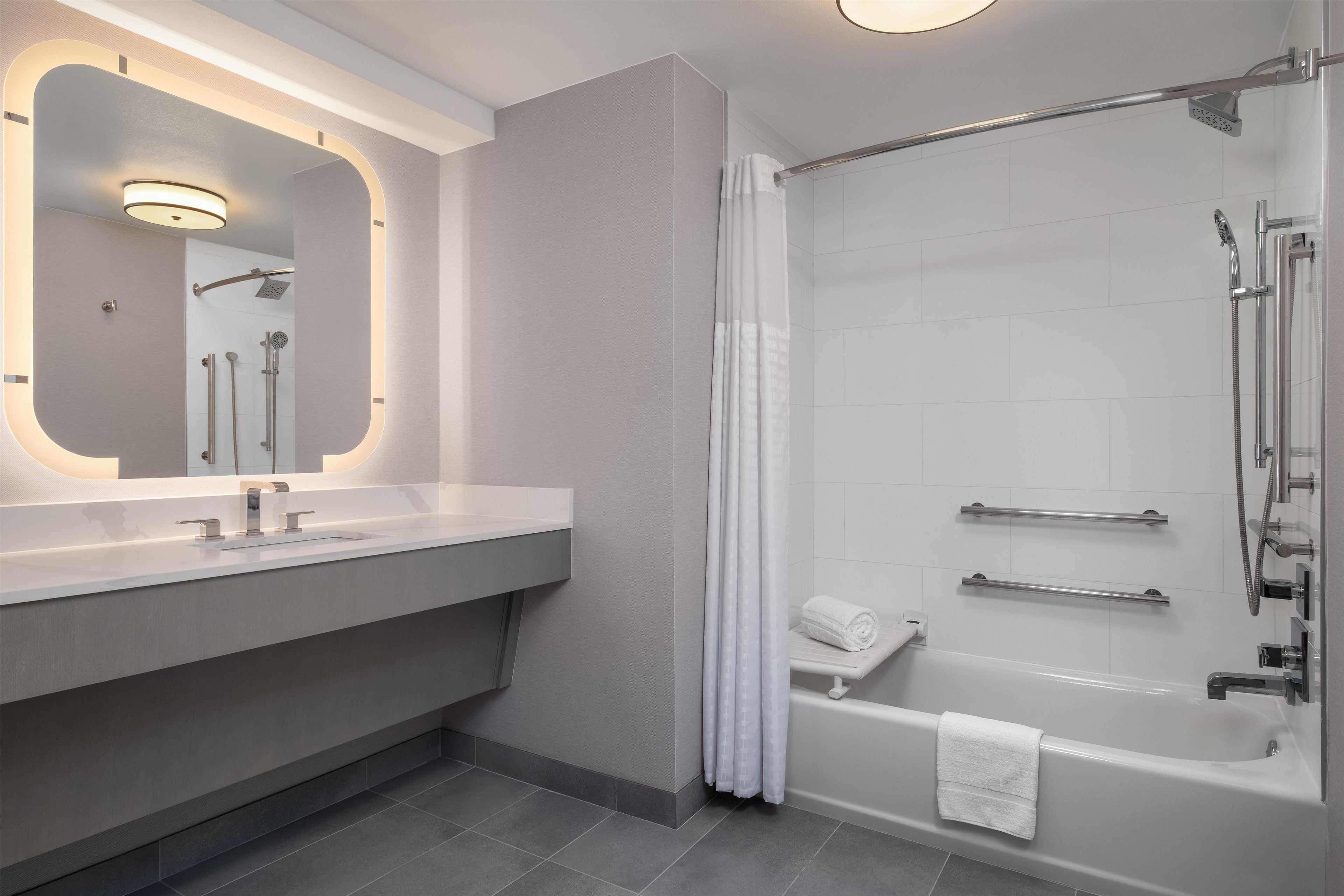 A modern bathroom with a large mirror, a sink, a shower, and a bathtub.