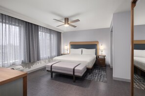 Una habitación de hotel con cama, mesitas de noche, un escritorio y un ventilador de techo.