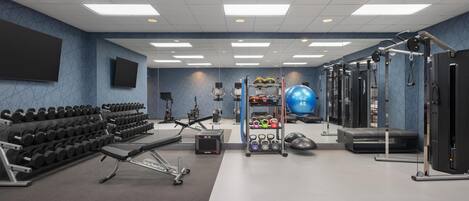 A gym with weightlifting equipment, exercise balls, and dumbbells.