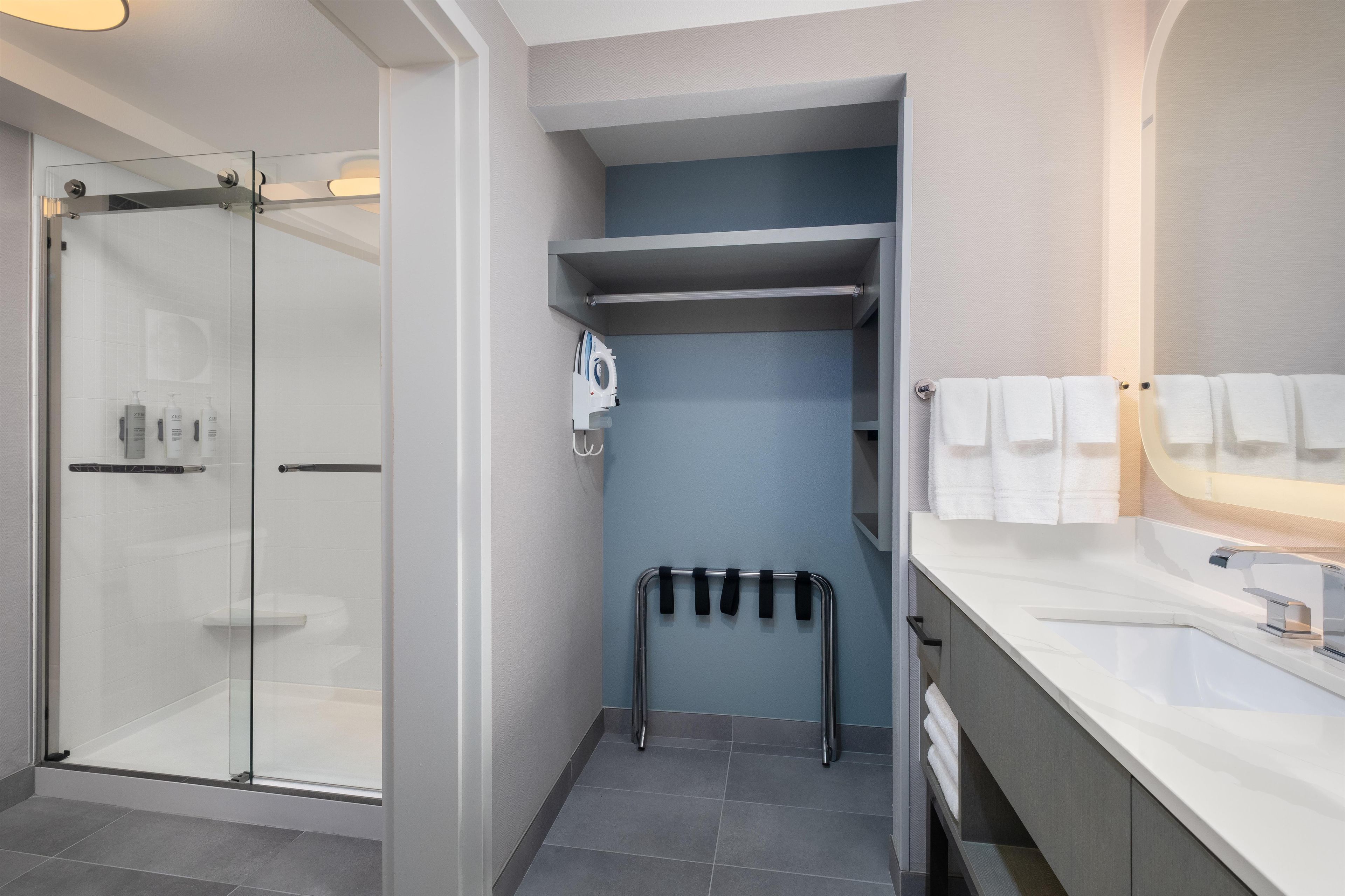 A modern bathroom with a glass shower enclosure, a built-in towel rack, and a vanity with a mirror.