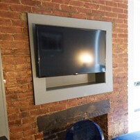 A flat-screen TV mounted on a brick wall.
