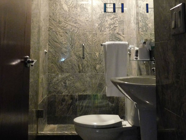 Un bagno con una parete in marmo, un water, un lavandino e un asciugamano appeso a un porta-asciugamani.
