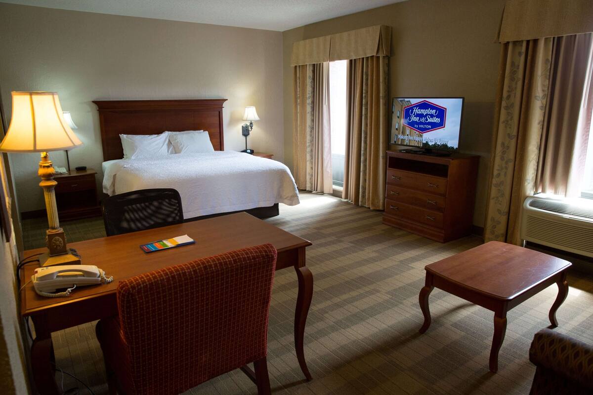 A hotel room with a bed, a television, a desk, and a chair.