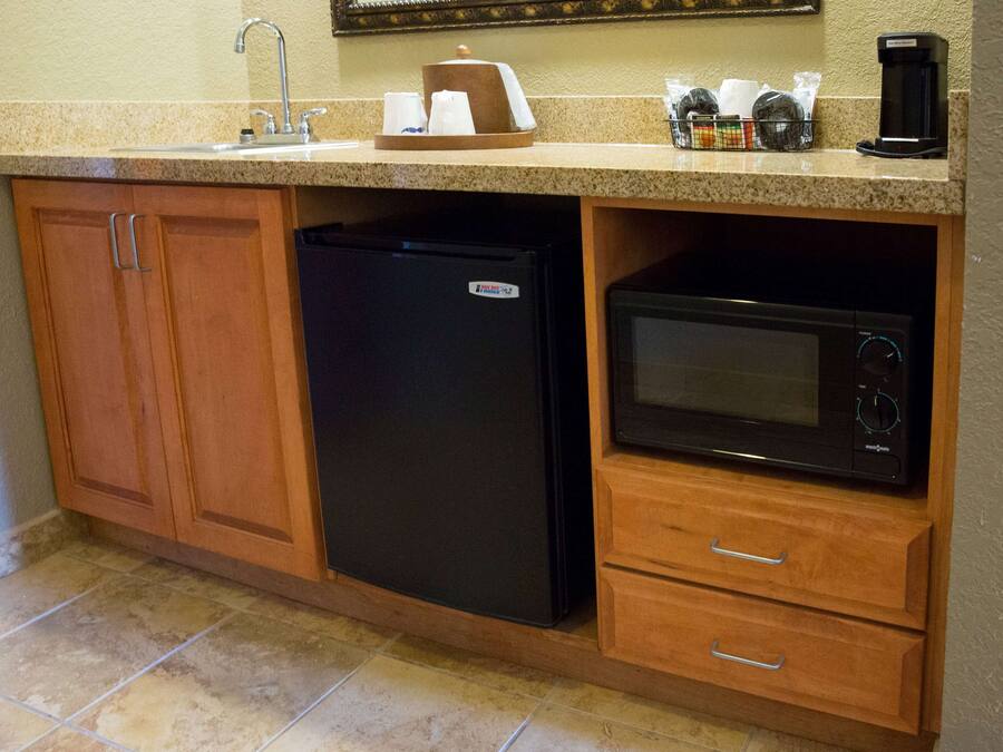 Cocina compacta con refrigerador, microondas y cafetera sobre la encimera.