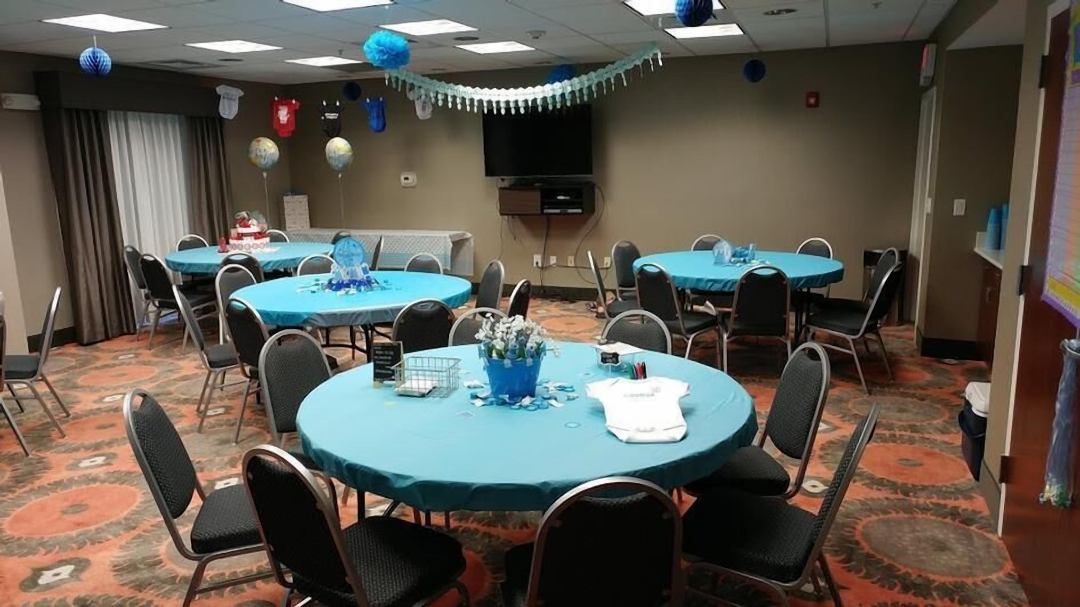 A conference room with round tables, chairs, and a television.
