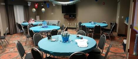A conference room with round tables, chairs, and a television.