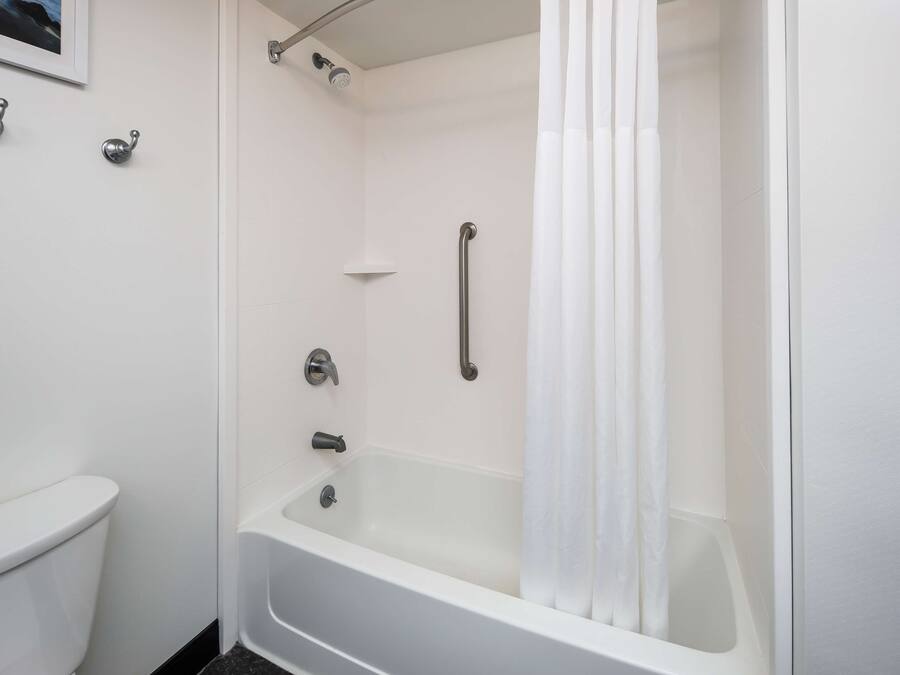A modern bathroom with a white bathtub, a shower, and a toilet.