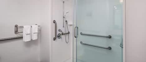 A modern bathroom with a glass shower enclosure, a towel rack with white towels, and a glass door with a handle.