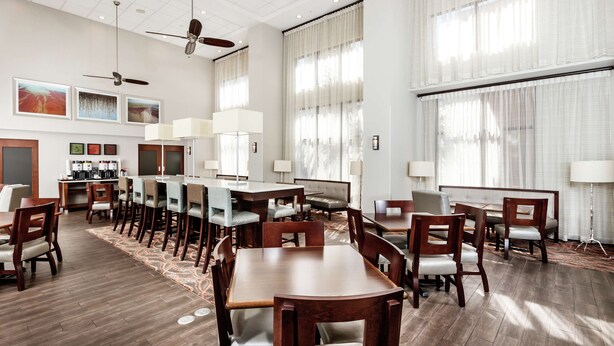 A spacious dining area with high ceilings, ceiling fans, and large windows with sheer curtains. - Hampton Inn & Suites Navarre (Navarre)