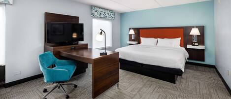 A hotel room with a bed, a desk with a chair, a television, and two bedside lamps.